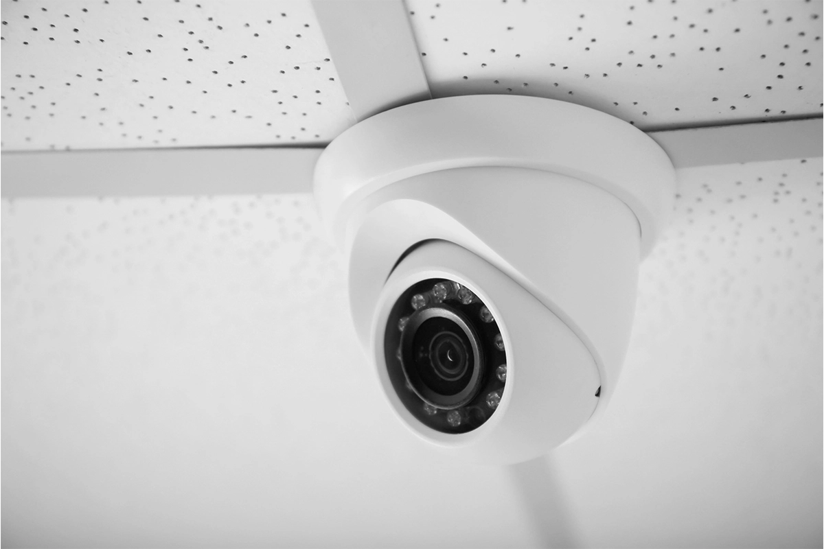 Close-up of a white dome security camera mounted on a ceiling.