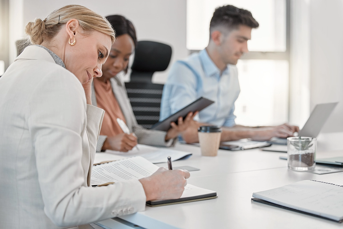 Boardroom Taking Notes - Computer Headquarters Business professionals in a meeting taking notes and collaborating with laptops and tablets in a modern office.