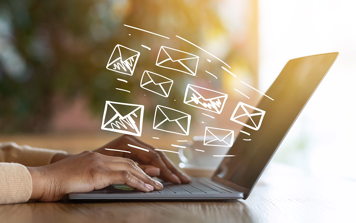 Numerous Emails - Computer Headquarters Hands typing on laptop with illustrated email icons representing high email volume and digital communication.