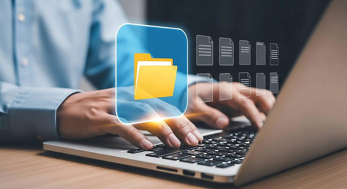 Person typing on a laptop with a digital folder icon hovering above the keyboard, symbolizing file sharing and secure data storage.