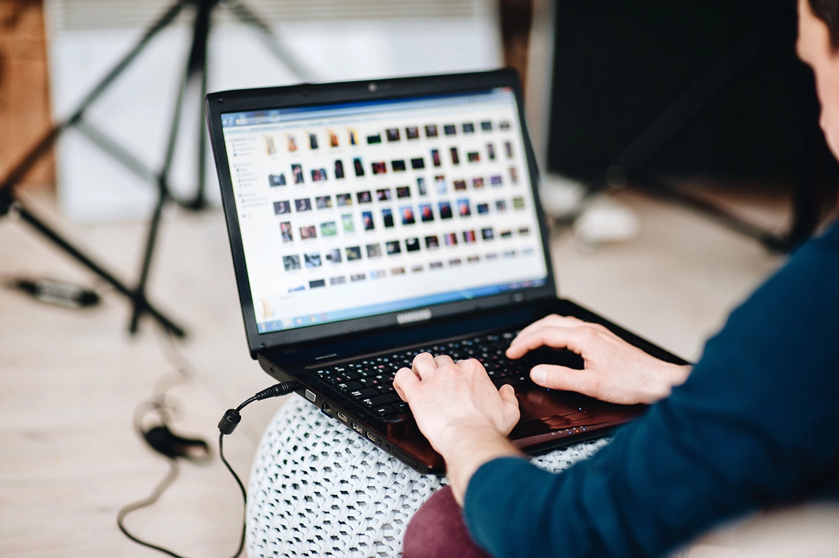 Person organizing photo and file folders on a laptop, illustrating digital file management and cloud storage organization.
