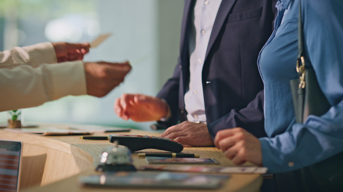 Business front desk scene with staff assisting customers at a counter, showing in person service and transaction handling.