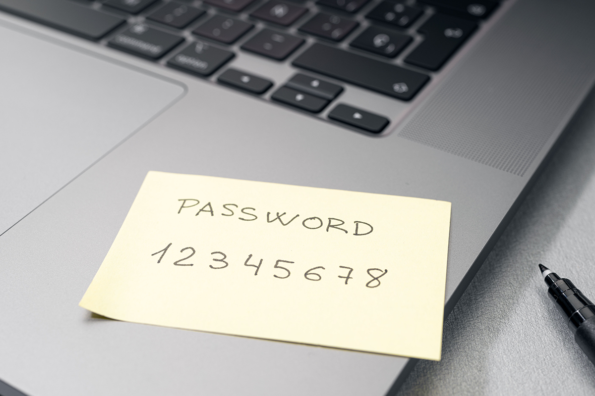 Sticky note labeled “password” with a simple numeric sequence placed on a laptop keyboard, illustrating poor password security practices.