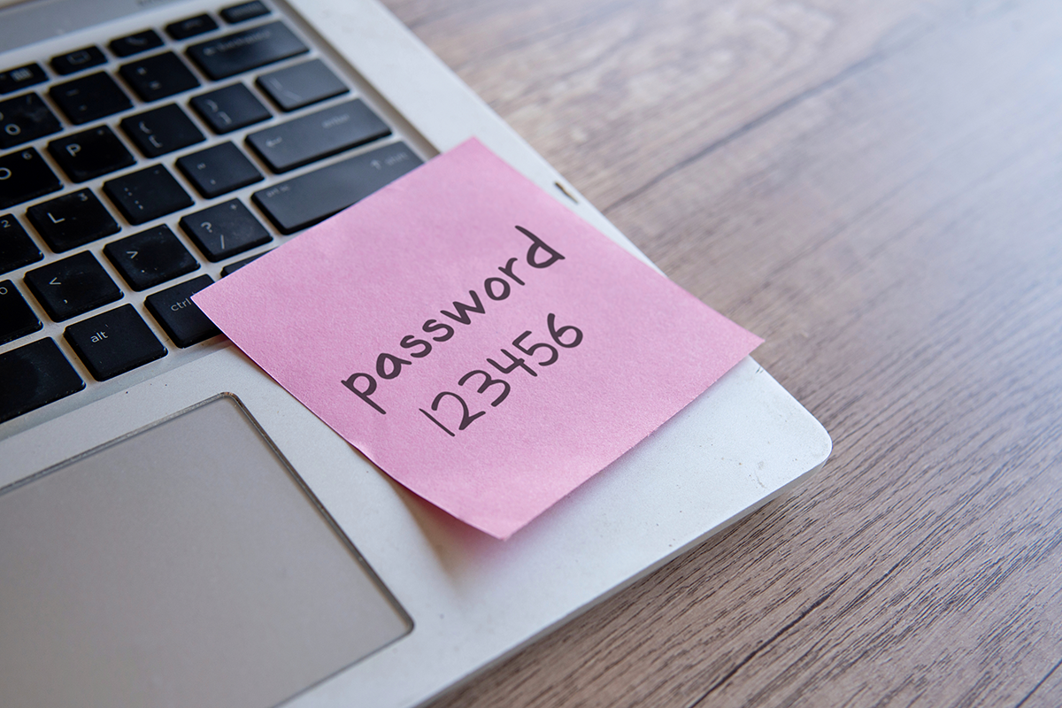 Sticky note with a handwritten password placed on a laptop keyboard, representing insecure password storage practices.