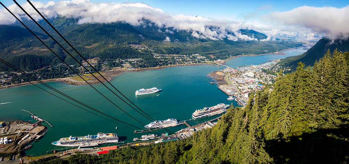 Aerial view of cruise ships docked in Juneau Alaska harbor surrounded by forested mountains