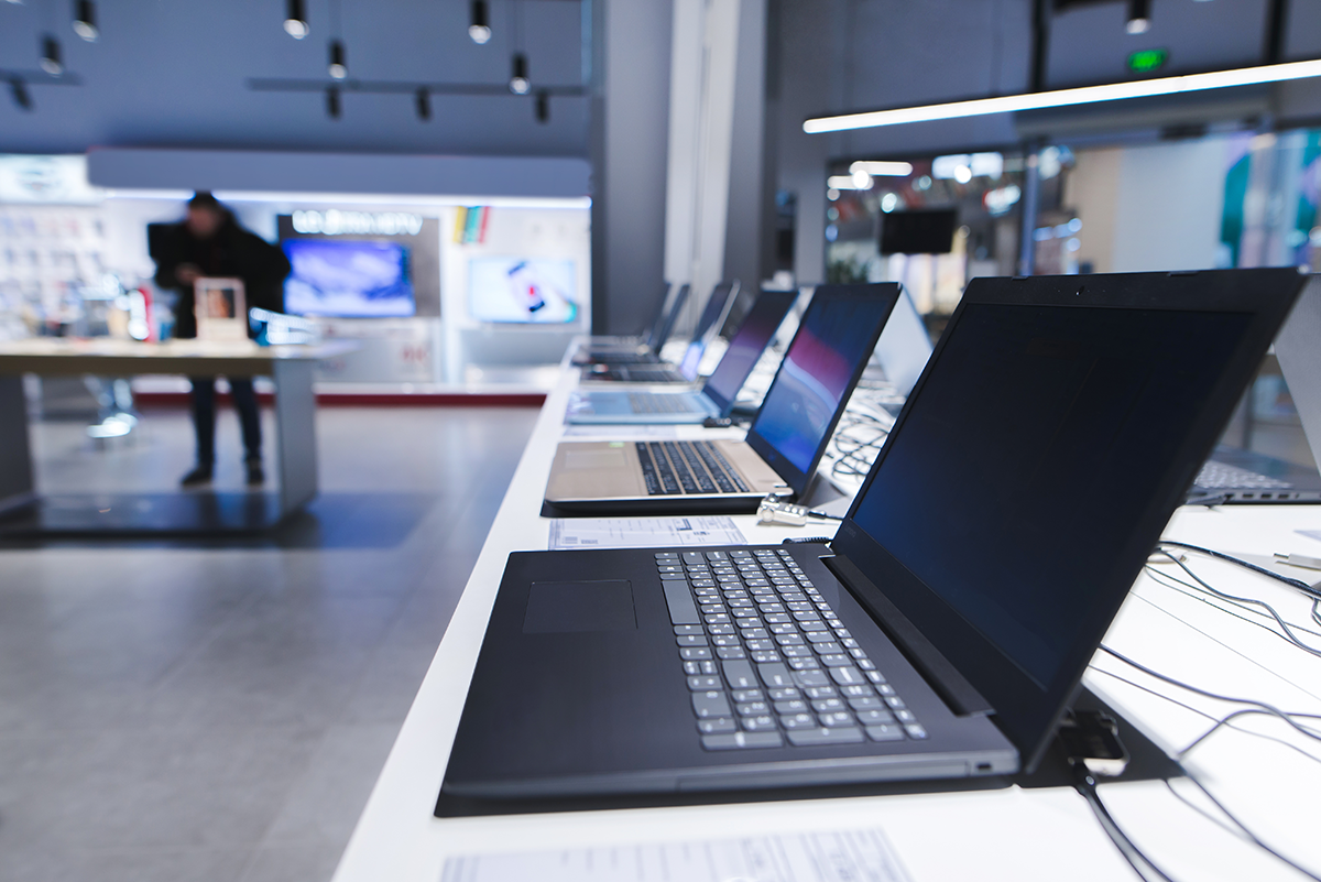 Row of modern laptops on display in retail electronics store showroom