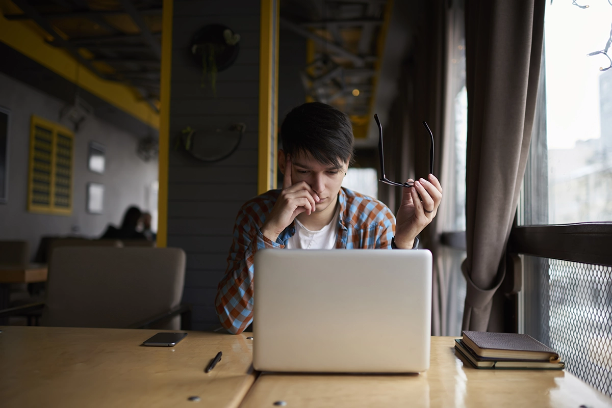 Person sitting at table focused on laptop, representing work, productivity, or online activity