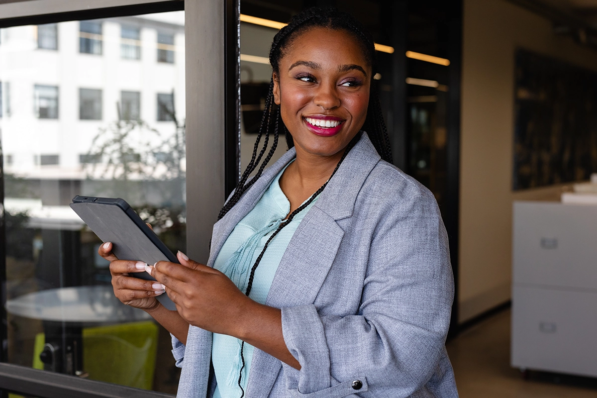 Business professional holding tablet in modern office environment, reviewing digital content
