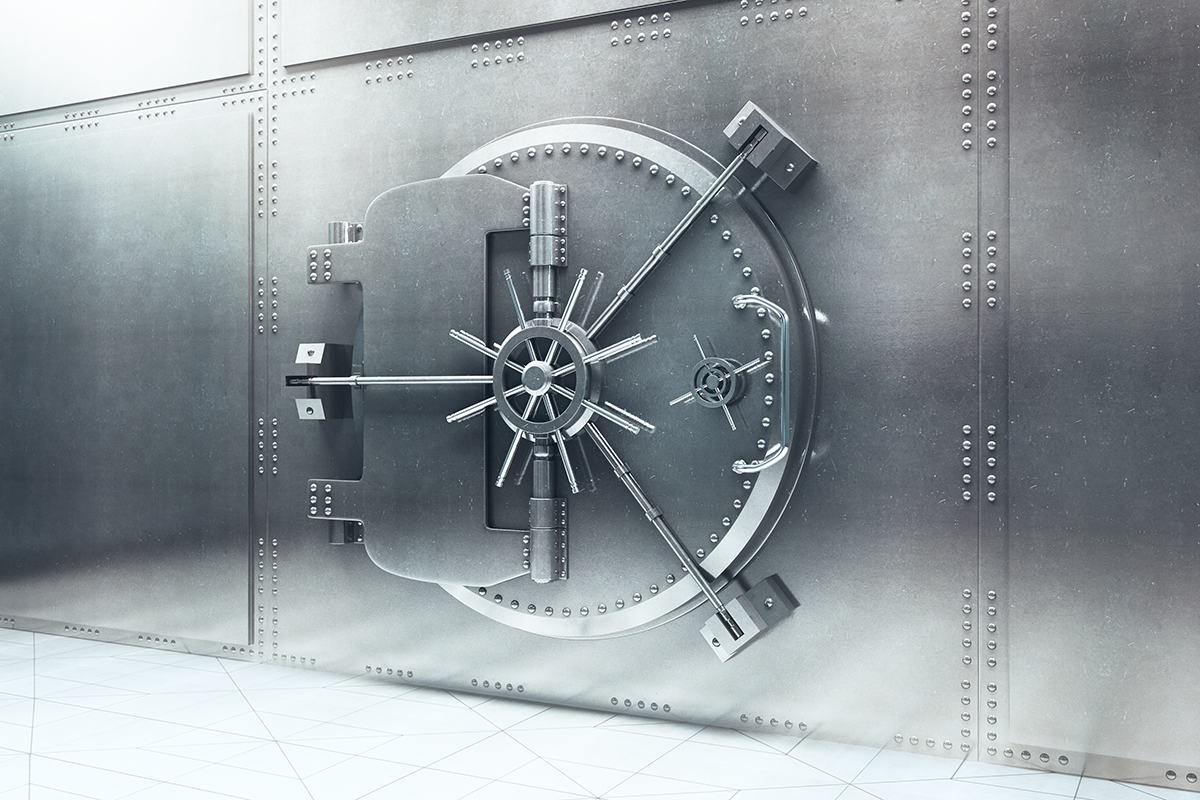 Heavy metal bank vault door with a large circular spoked locking wheel and reinforced bolts on a riveted safe wall.