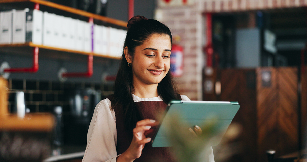 Smiling café employee uses a tablet behind the counter, suggesting normal service after connectivity has been restored.